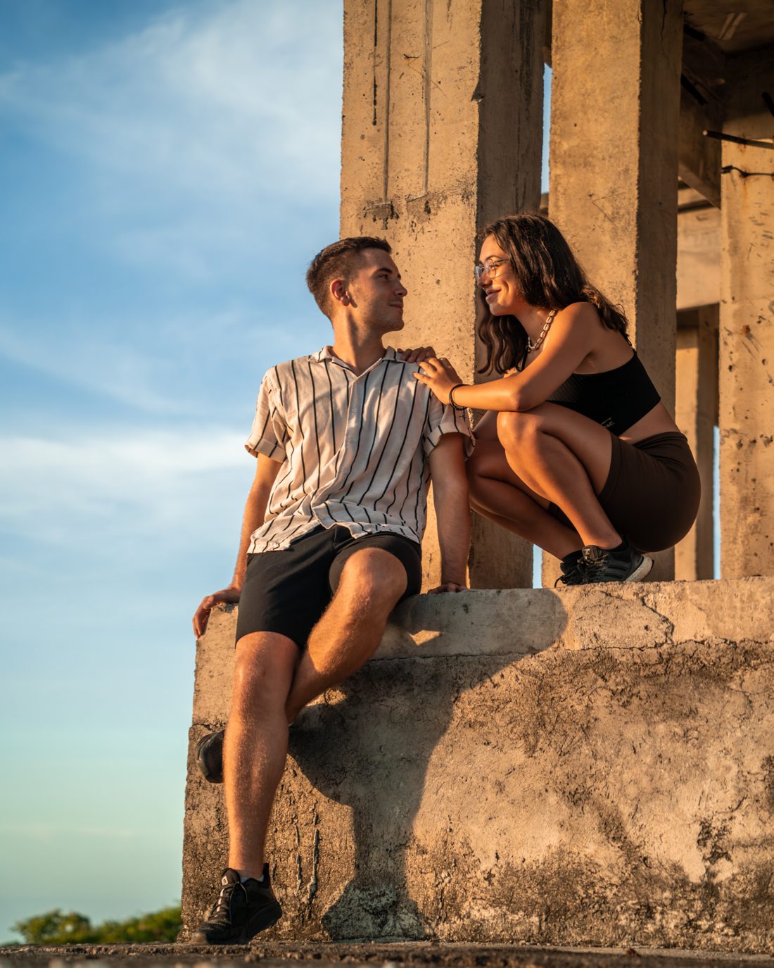 Clara und Jonathan sitzen auf einer alten Steinmauer über dem Meer