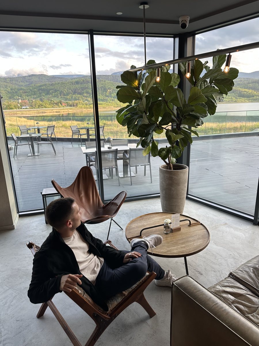Jonathan mit Laptop im Sessel vor einer Fensterfront